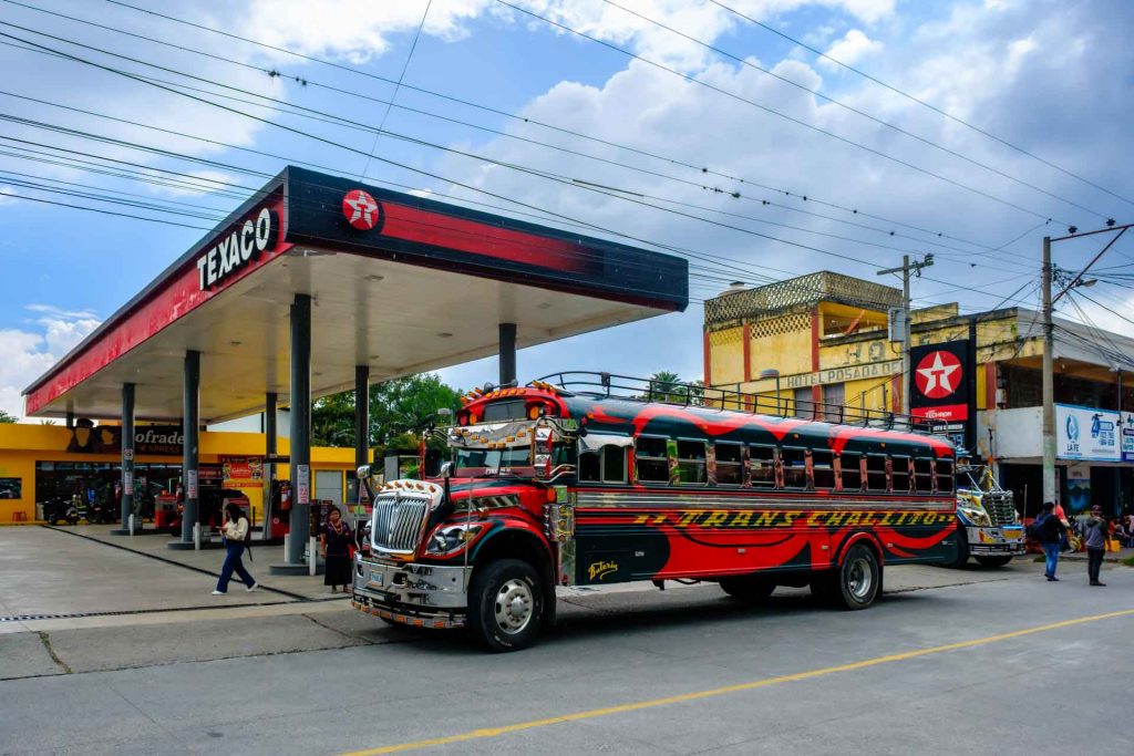 Red chicken bus driving along a busy street in Guatemala City.