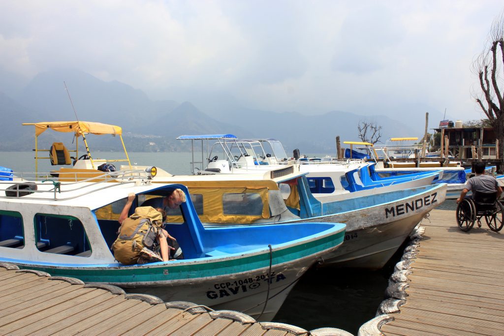 Travelers boarding a lancha boat between towns on Lake Atitlan, showing local transportation costs.